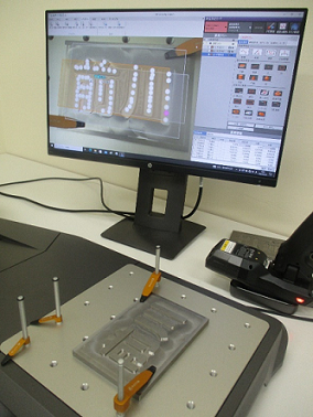訓練生が加工した金型を三次元測定機で測定している写真