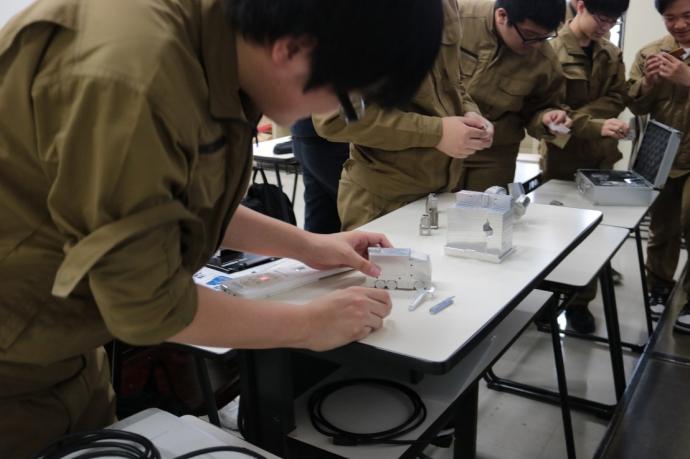 マシニングセンタで加工した製品を訓練生が手に取っている写真